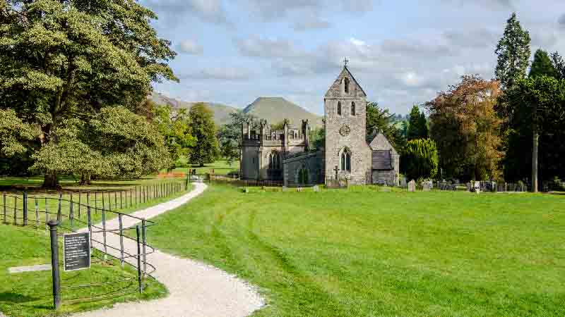 Exterior view of Holy Cross Church, a historic building set against the quiet Chess Valley landscape.