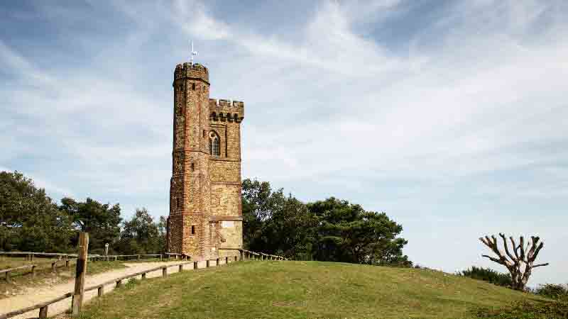 Leith Hill Tower standing on a grassy hillside under a bright sky